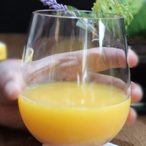 Hand holding glass of orange juice
