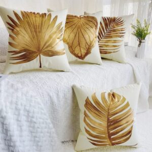 Leaf-patterned decorative pillows on white bedspread.